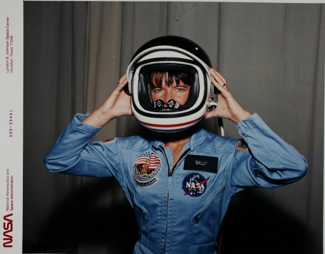 NASA's Sally K. Ride tries on her astronaut helmet facing the camera